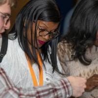three people peruse giveaways on table